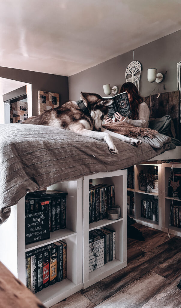 Woman reading on a custom king-size bookshelf bed surrounded by books.